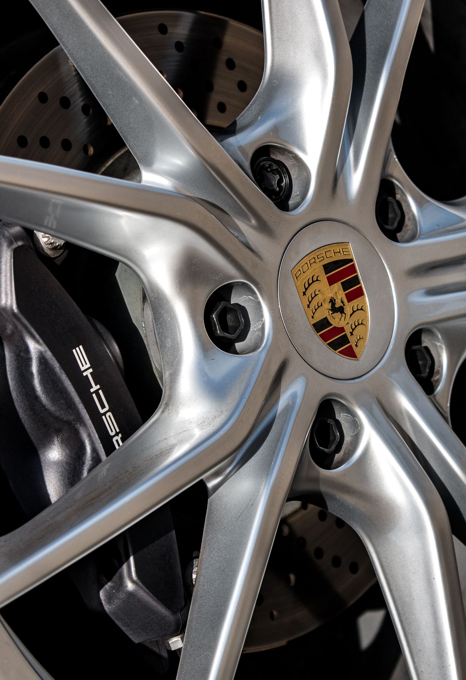Detail shot of a silver Porsche alloy wheel with brake disc and center cap logo.