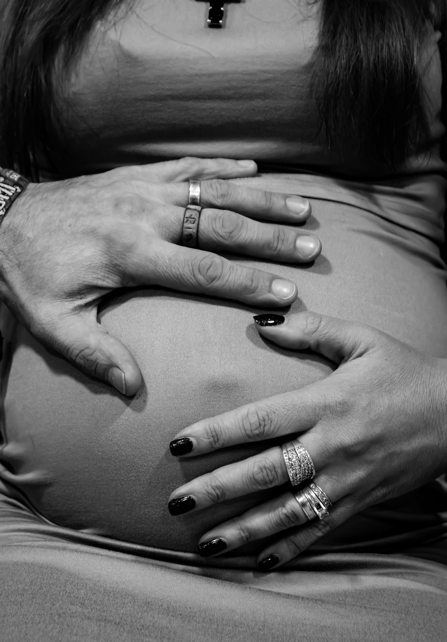 Series of black and white images showing hands tenderly placed on a pregnant belly.