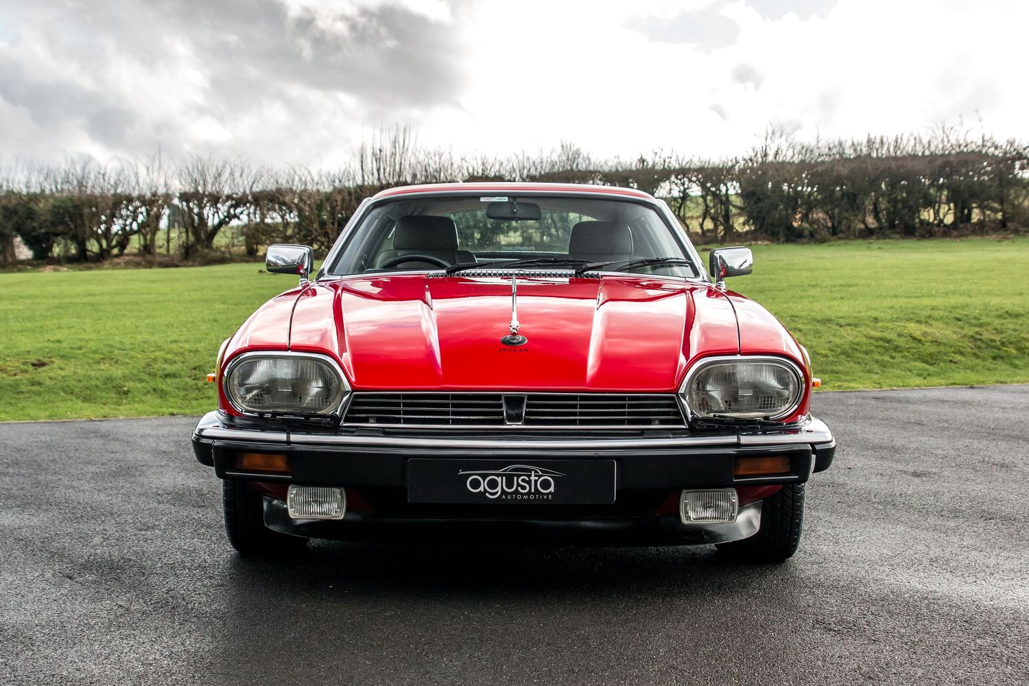 Classic red Jaguar XJS grand tourer front view on country road.