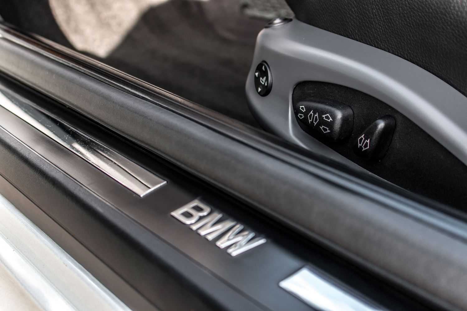 Close-up of BMW door sill with chrome trim and interior controls visible in a luxury BMW vehicle.