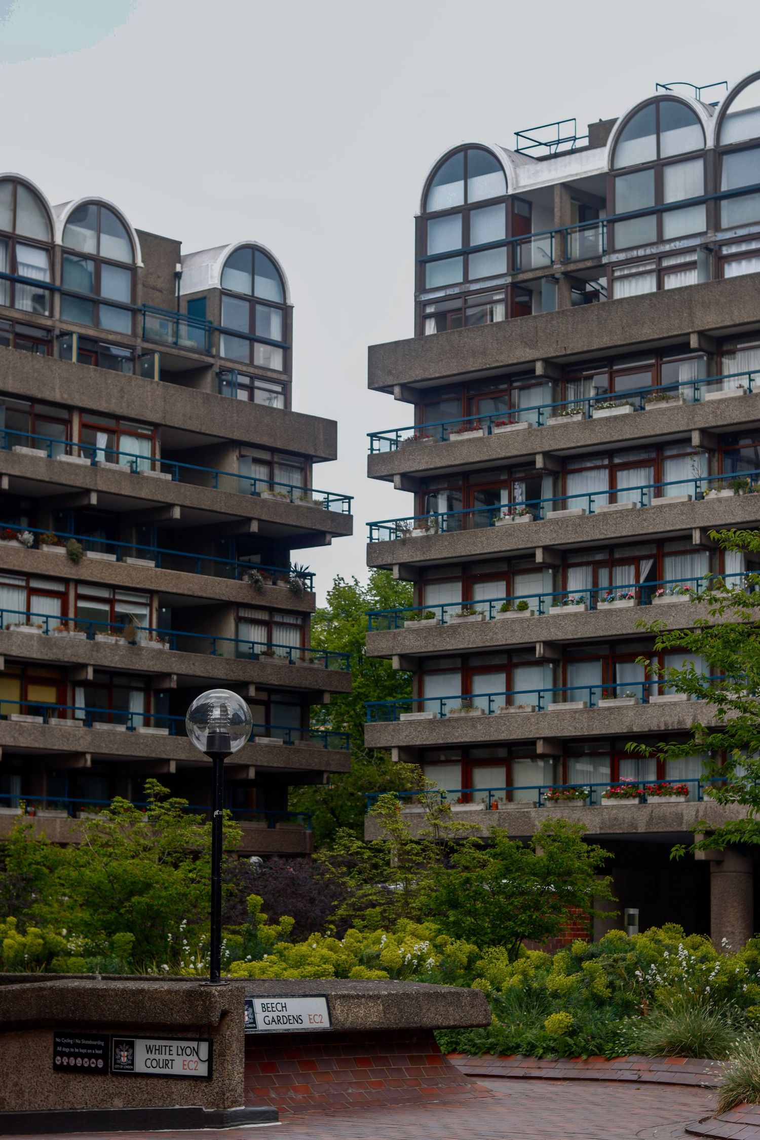 Modern apartment buildings with curved balconies overlooking a landscaped courtyard in an urban setting.