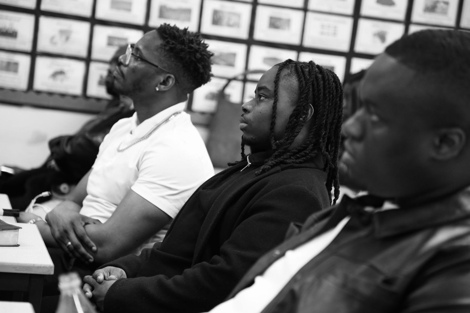 Black and white photo of people seated indoors, attentively watching or listening during a group session.