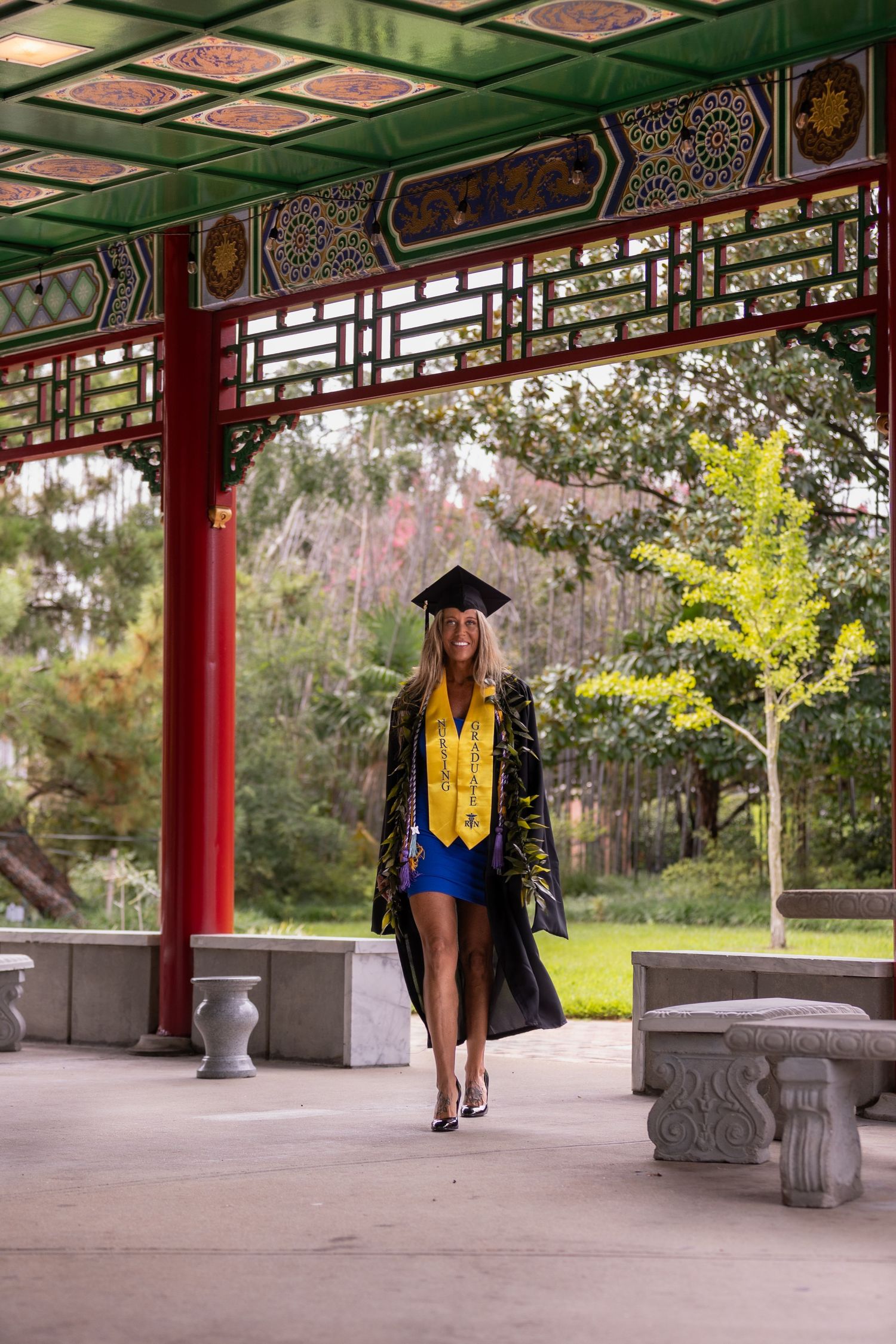 Nurse graduate walking with cap and gown, nature in background