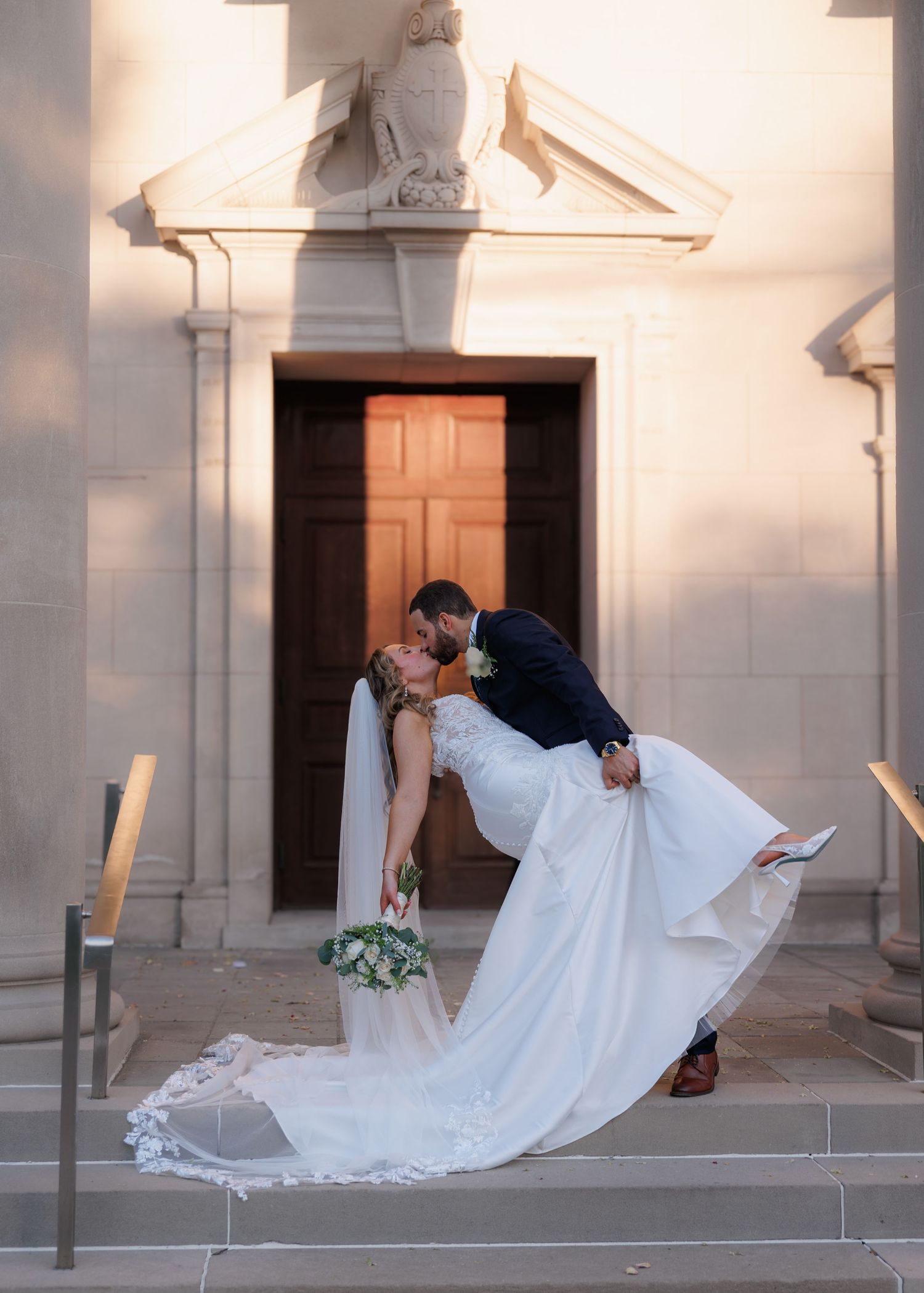 bride and groom kissing in front of chapel