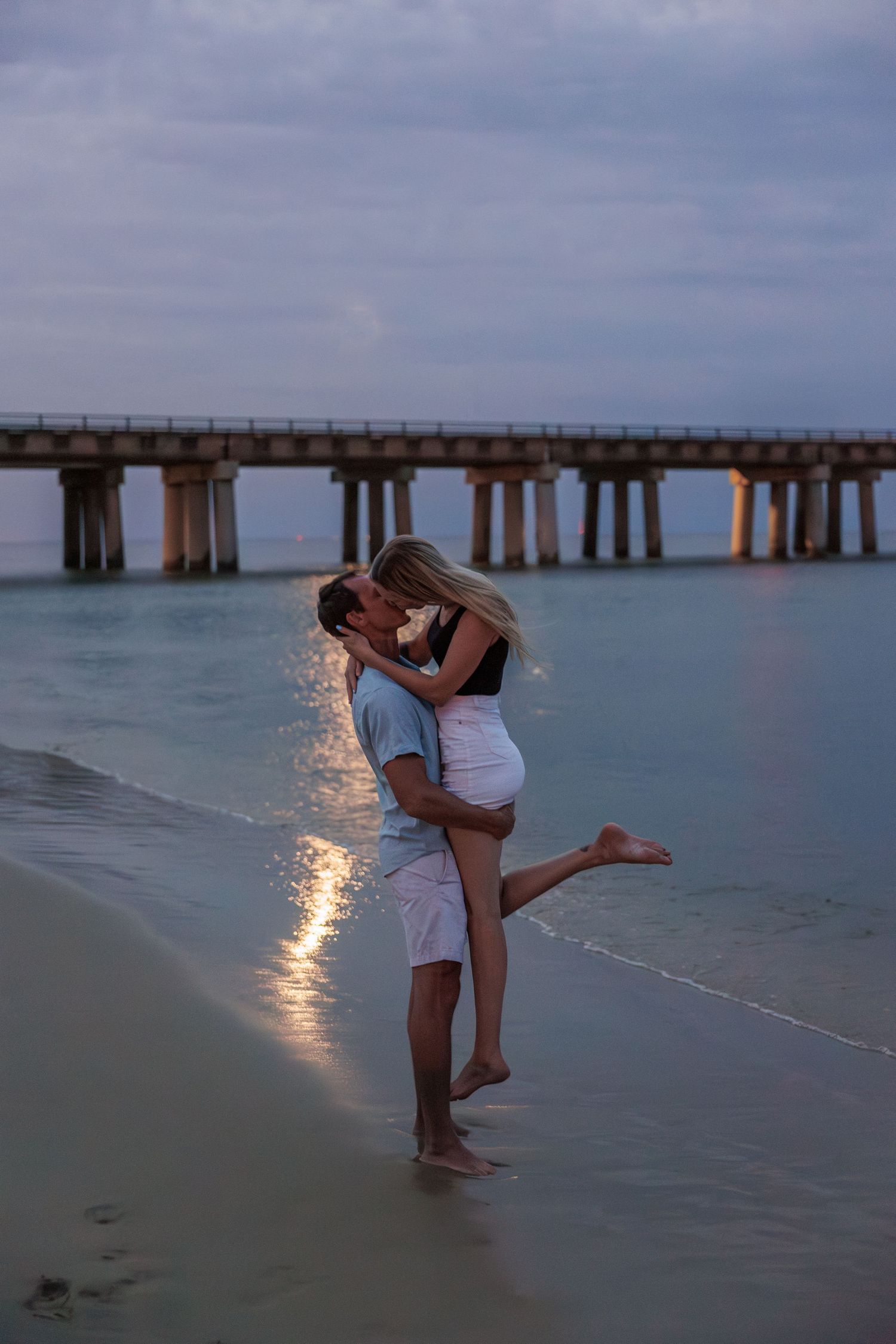 couple on beach kissing, hes lifting her in the air