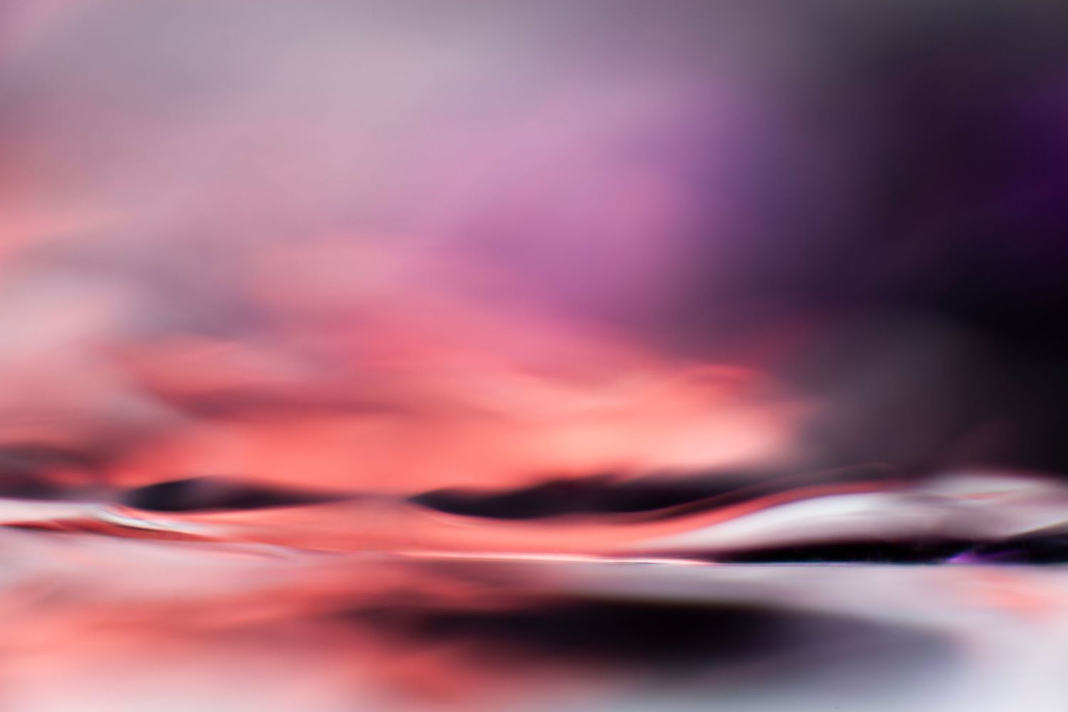 Abstract blurred pink and purple landscape with soft flowing waves and dreamy bokeh light effects.