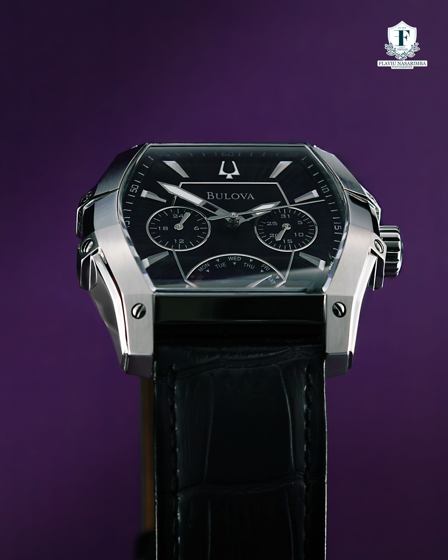 Bulova curved tonneau-shaped watch with black multi-function dial and alligator leather strap.