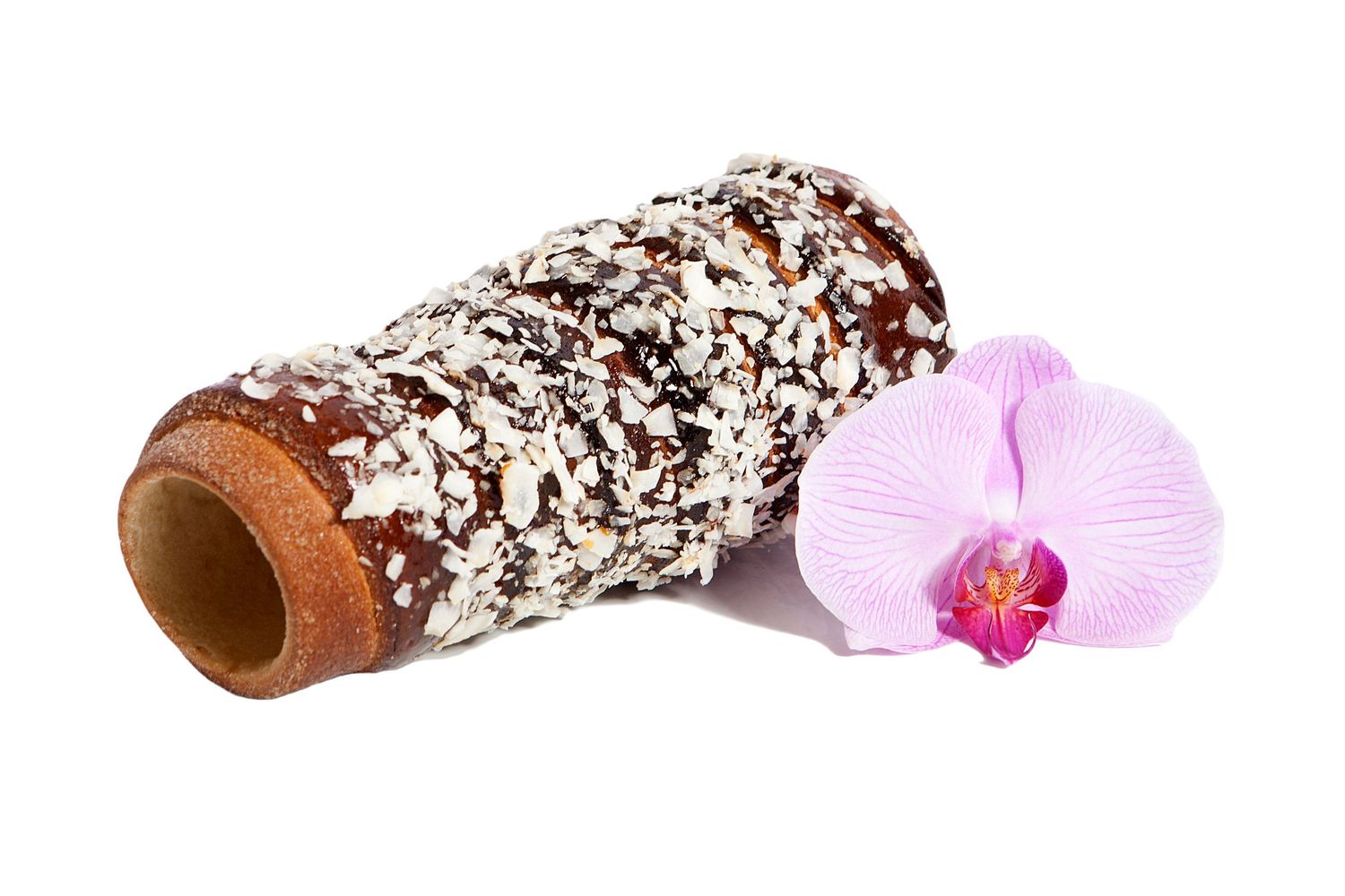 Chocolate-covered wafer roll with coconut flakes beside a pink orchid flower.