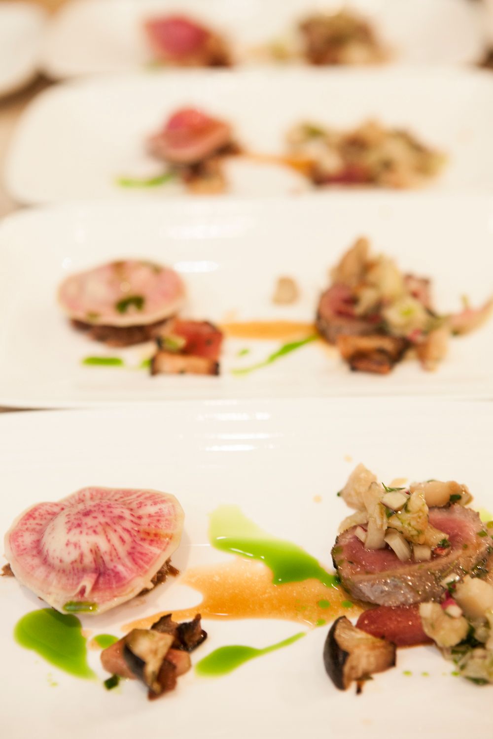 Fine dining tuna dish with watermelon radish, mushroom ragout, and vibrant green herb sauce.