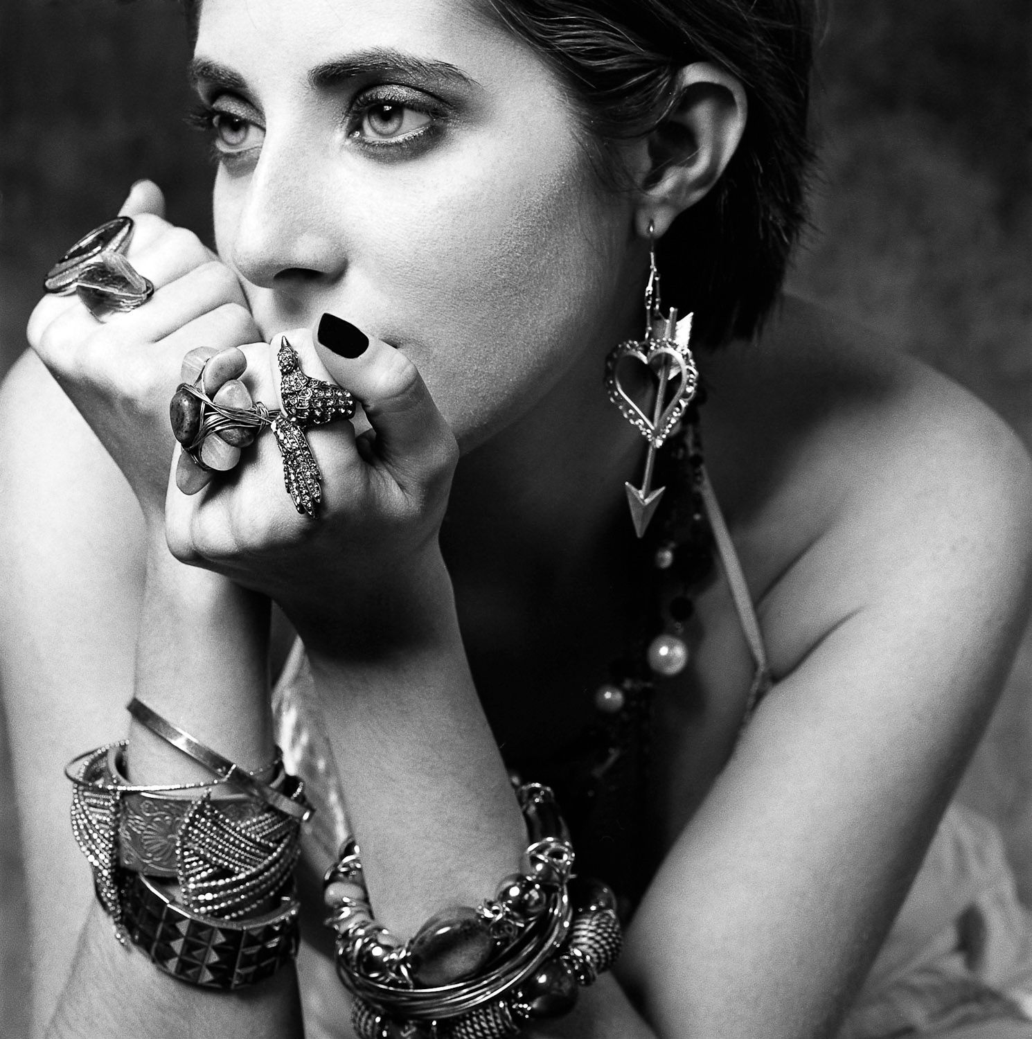 Black and white portrait of a woman adorned with statement rings, bracelets, and earrings.
