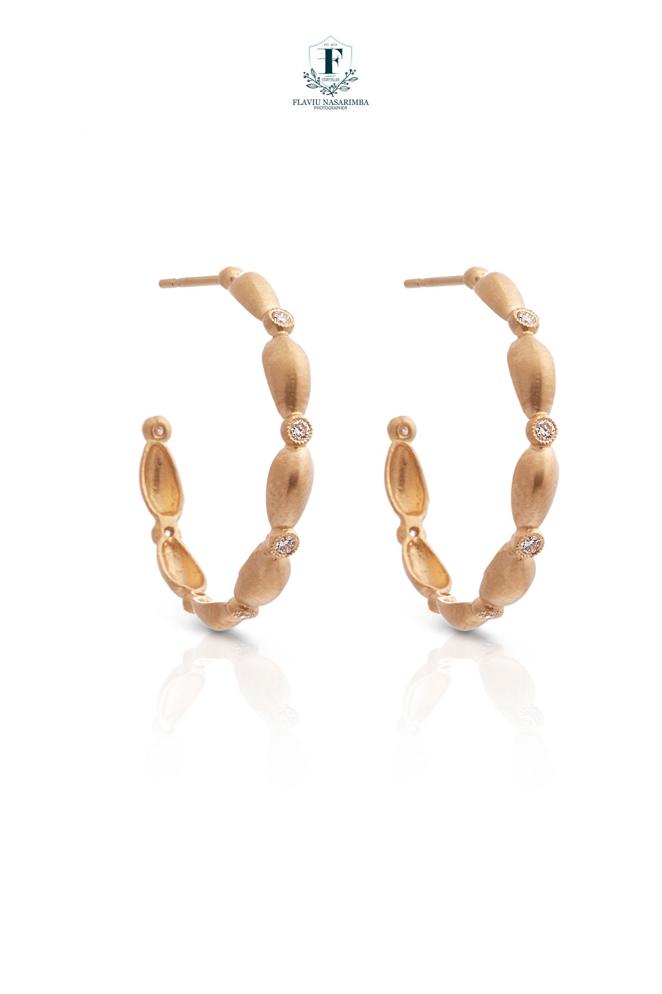 Rose gold hoop earrings with matte oval bead design and small diamond accent stations throughout.