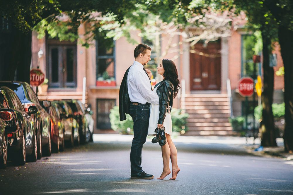 Couple facing each other intimately on a quiet New York City street lined with cars.