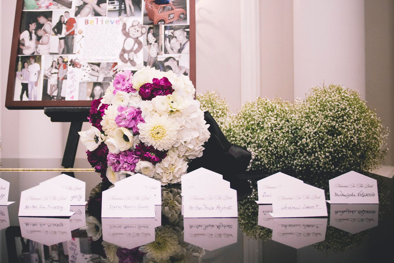 Wedding reception escort card table decorated with white and purple floral arrangements and baby's breath.