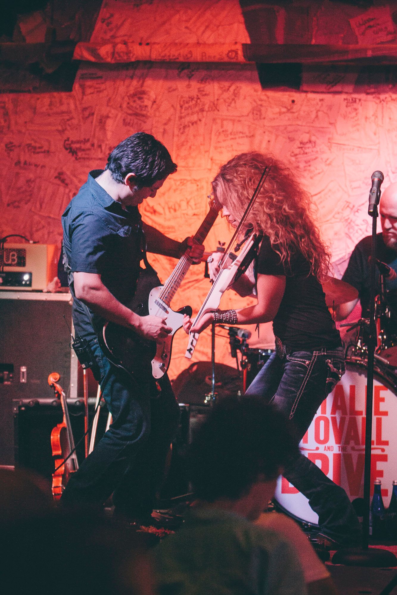 Male guitarist and female violinist face off on stage during an energetic live performance.