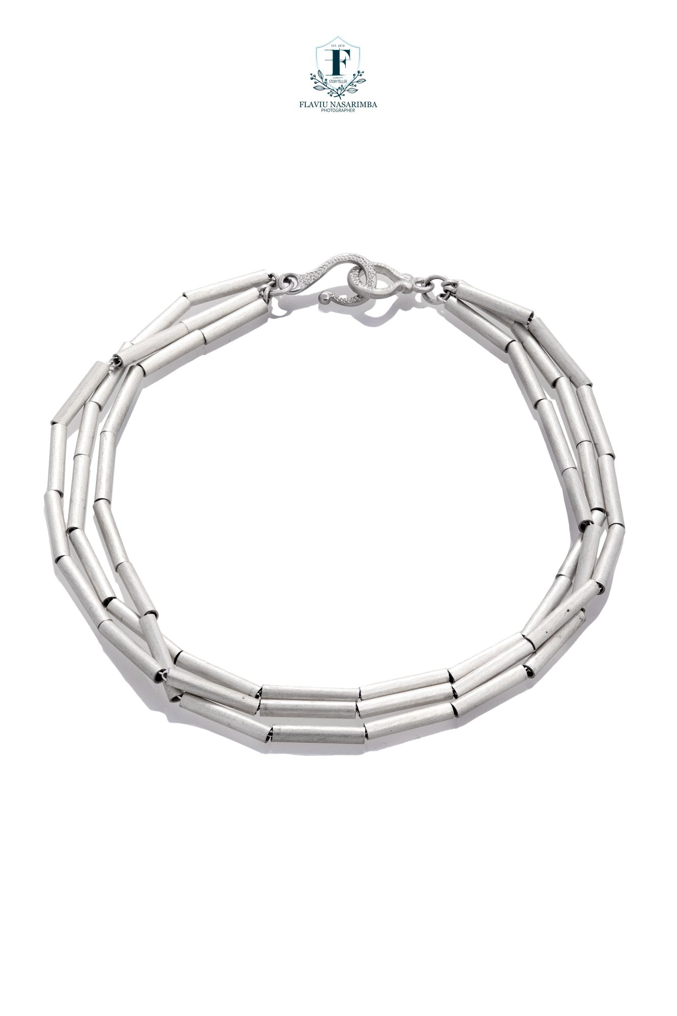 Triple-strand silver tube link bracelet with toggle clasp on white background.