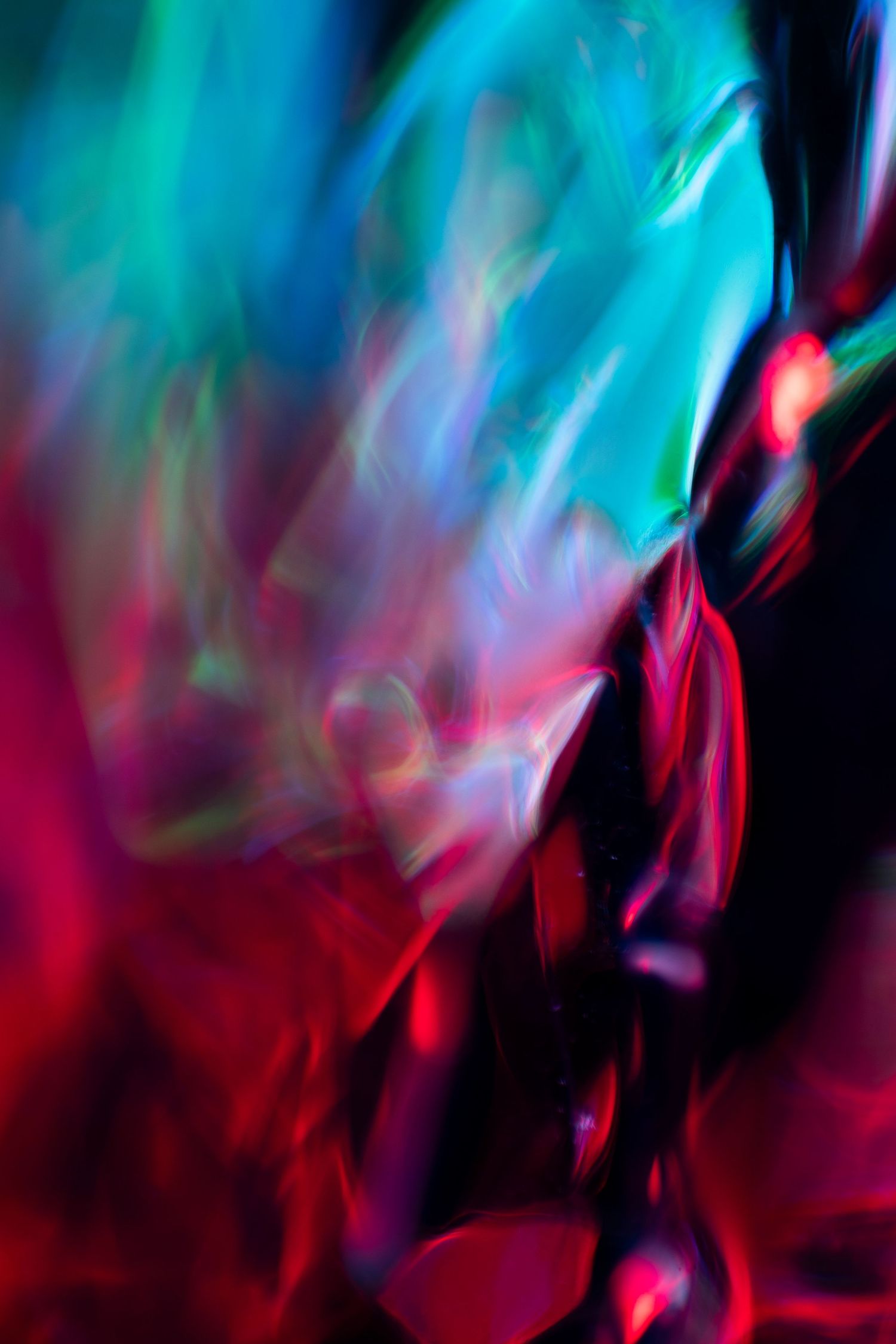 Abstract motion blur art with vibrant cyan, green, and red light streaks on dark background.