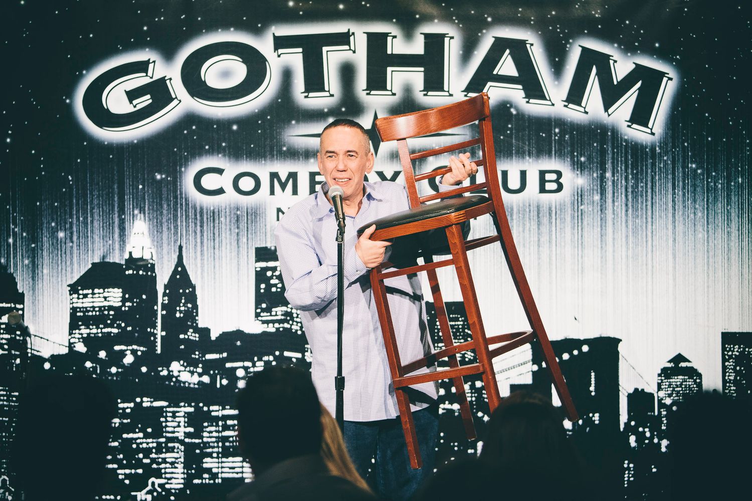 Comedian holding a wooden chair on stage at Gotham Comedy Club New York.