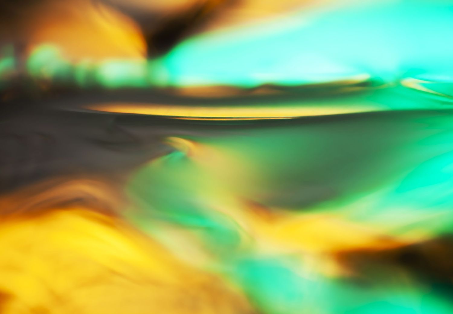 Abstract swirling blend of vibrant teal, green, and golden yellow hues creating a fluid, dreamy bokeh effect.