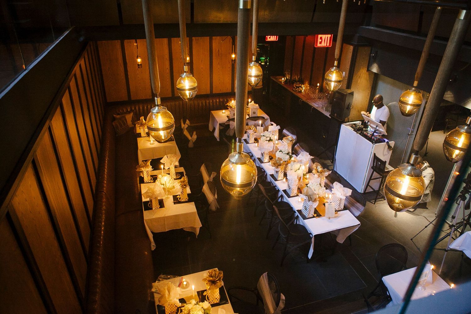 Aerial view of an elegant restaurant dining room with warm Edison bulb pendant lights and white tablecloth-covered tables.