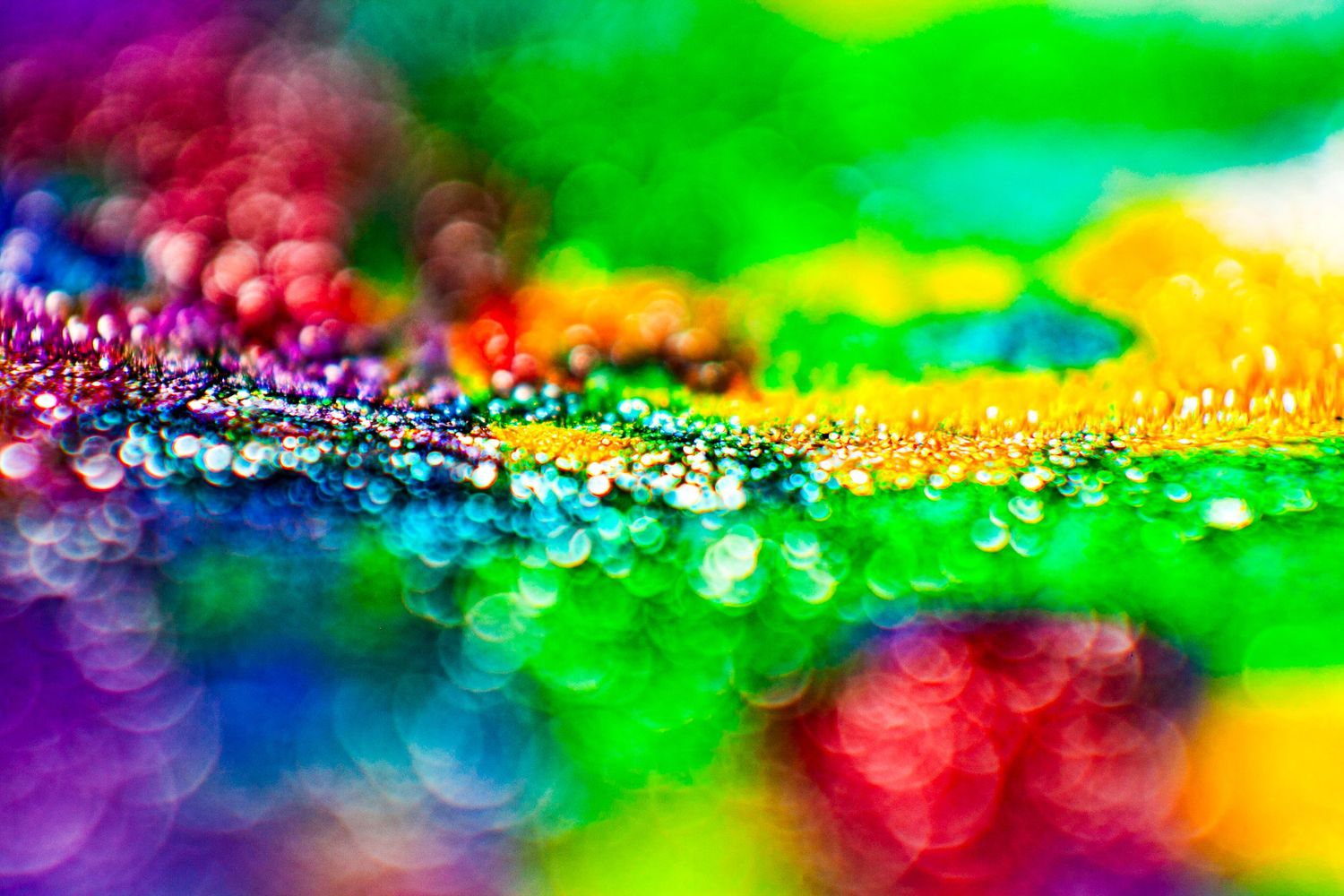 Vibrant macro photo of colorful bokeh lights with rainbow hues of green, purple, yellow, and red glittering droplets.
