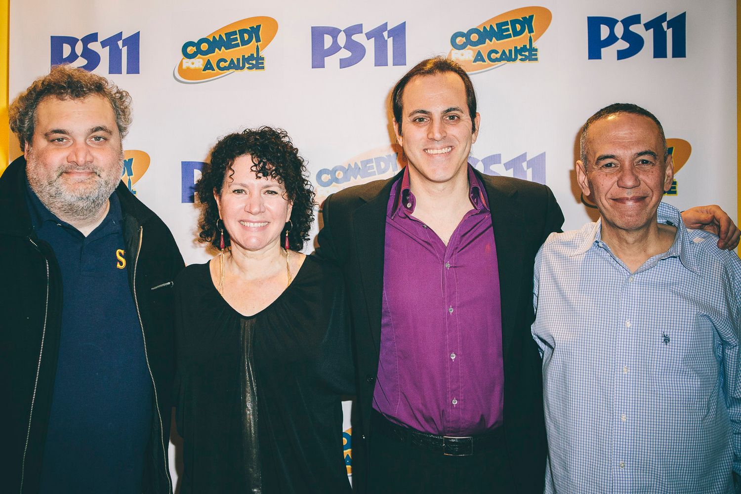 Four people posing together at PS11 Comedy for a Cause charity fundraiser event backdrop.