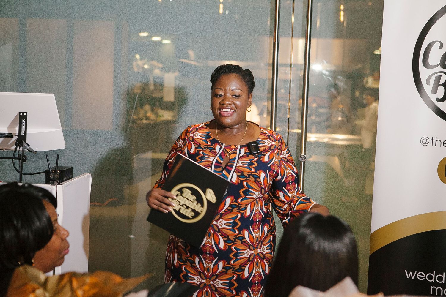 Smiling woman holding The Capable Bride branded book at a wedding planning event.