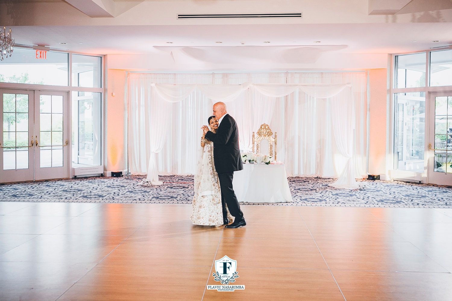 Bride and groom share their first dance in a beautifully decorated white ballroom at Indian wedding reception.