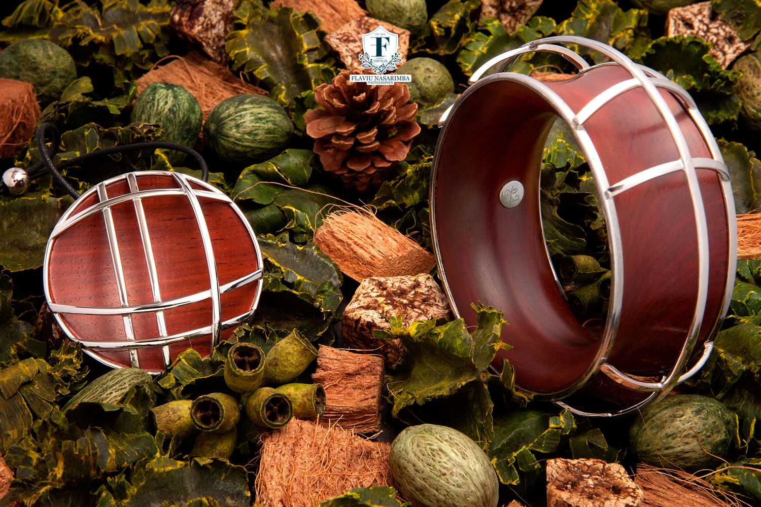 Dark red and silver geometric bracelet and pendant displayed among green moss and pine cones.