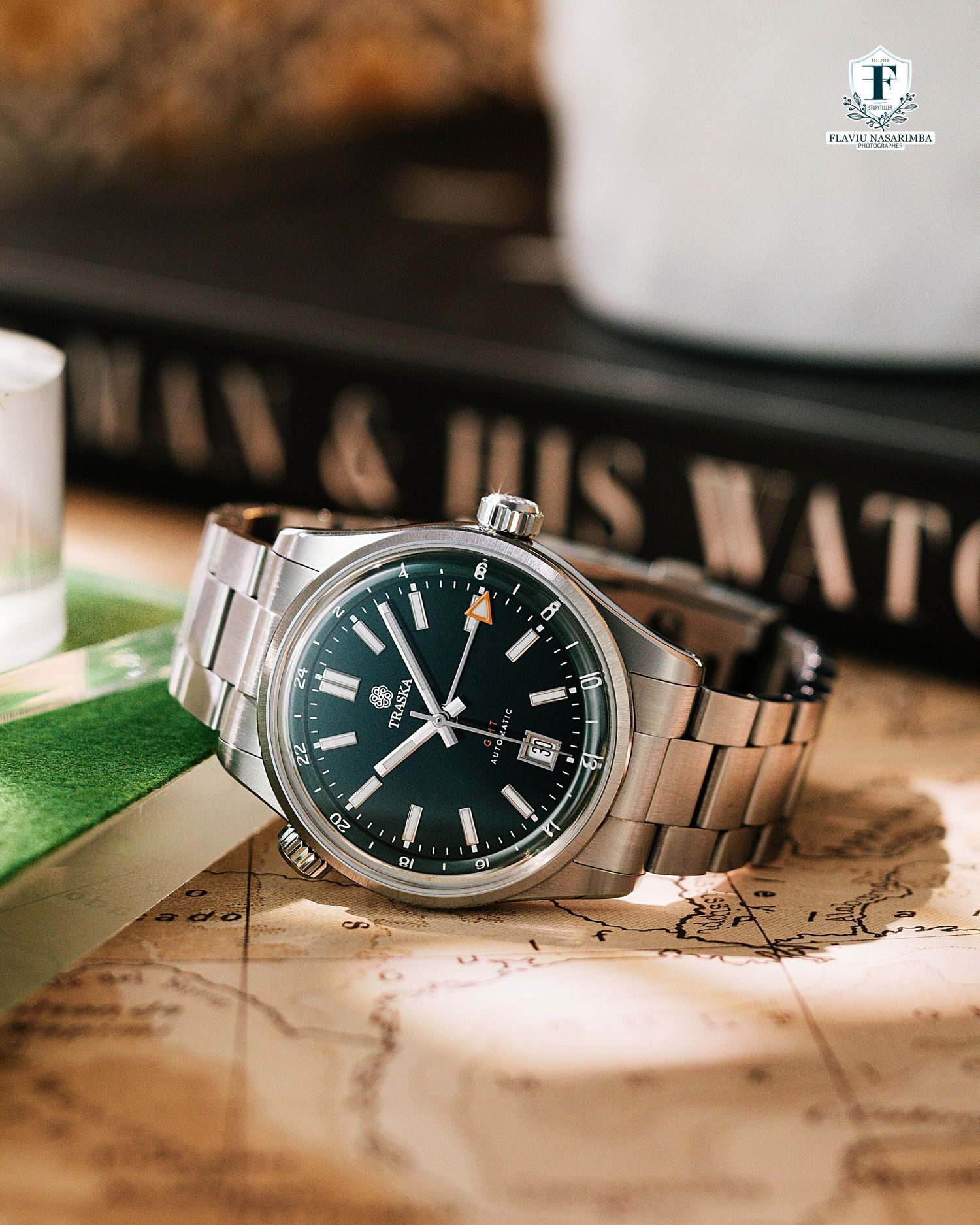 Green dial automatic watch on stainless steel bracelet resting on a vintage map.