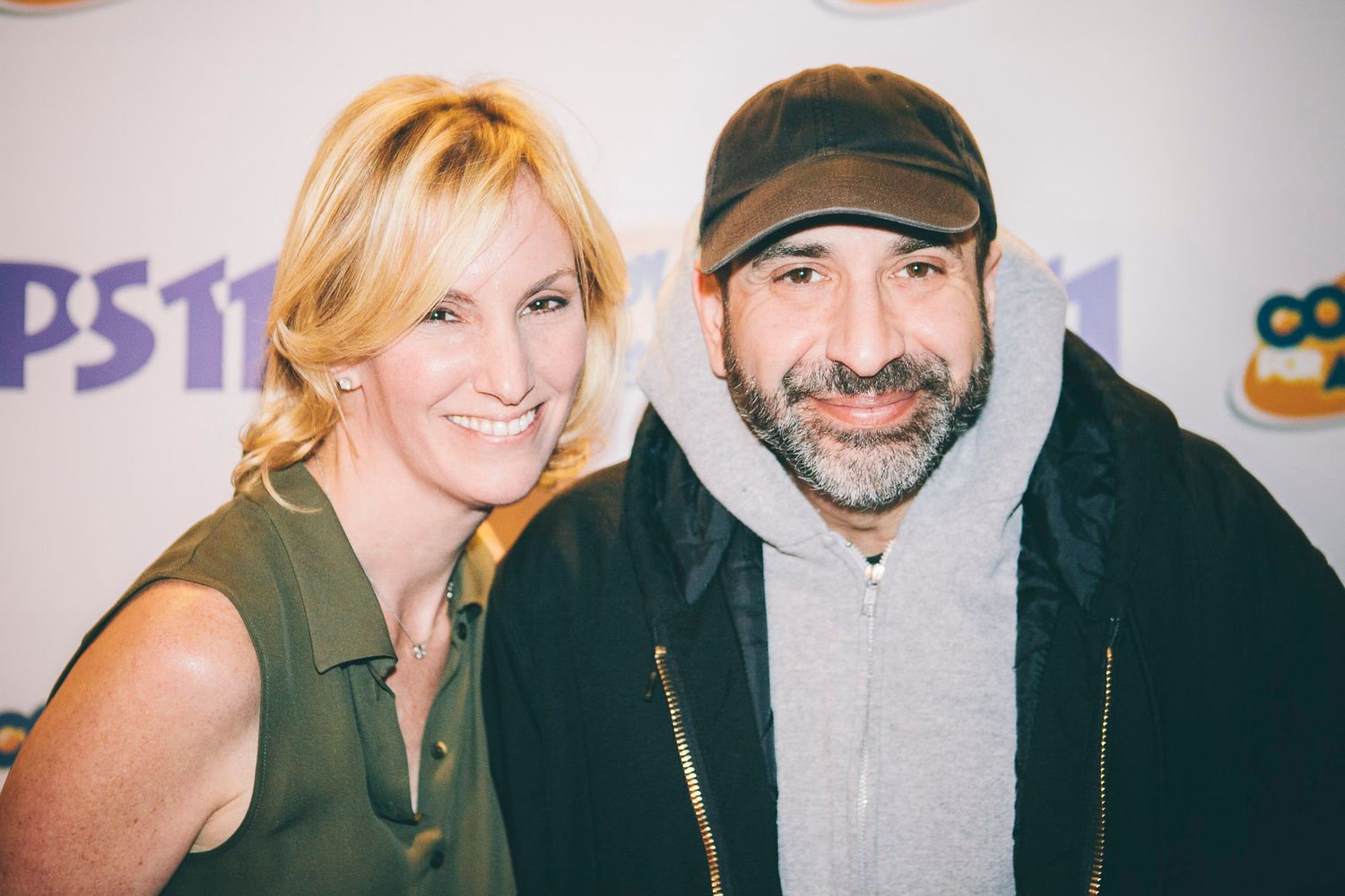 Two people smiling together at a PS11 comedy event backdrop.