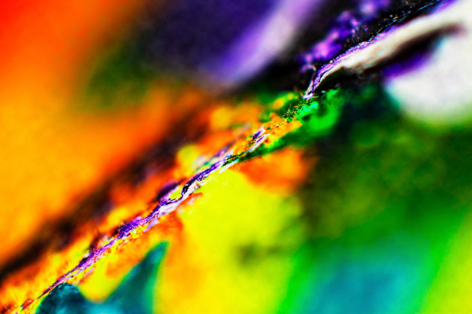 Vibrant macro abstract art with swirling rainbow colors including red, orange, yellow, green, and purple hues.