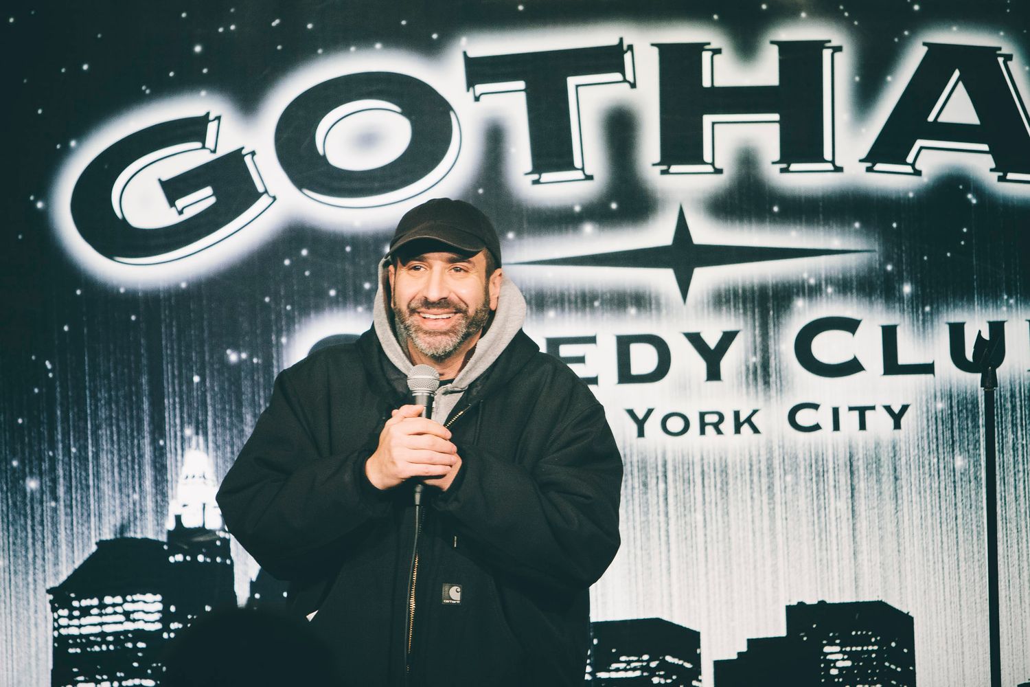Male comedian performing stand-up at Gotham Comedy Club New York City holding microphone.