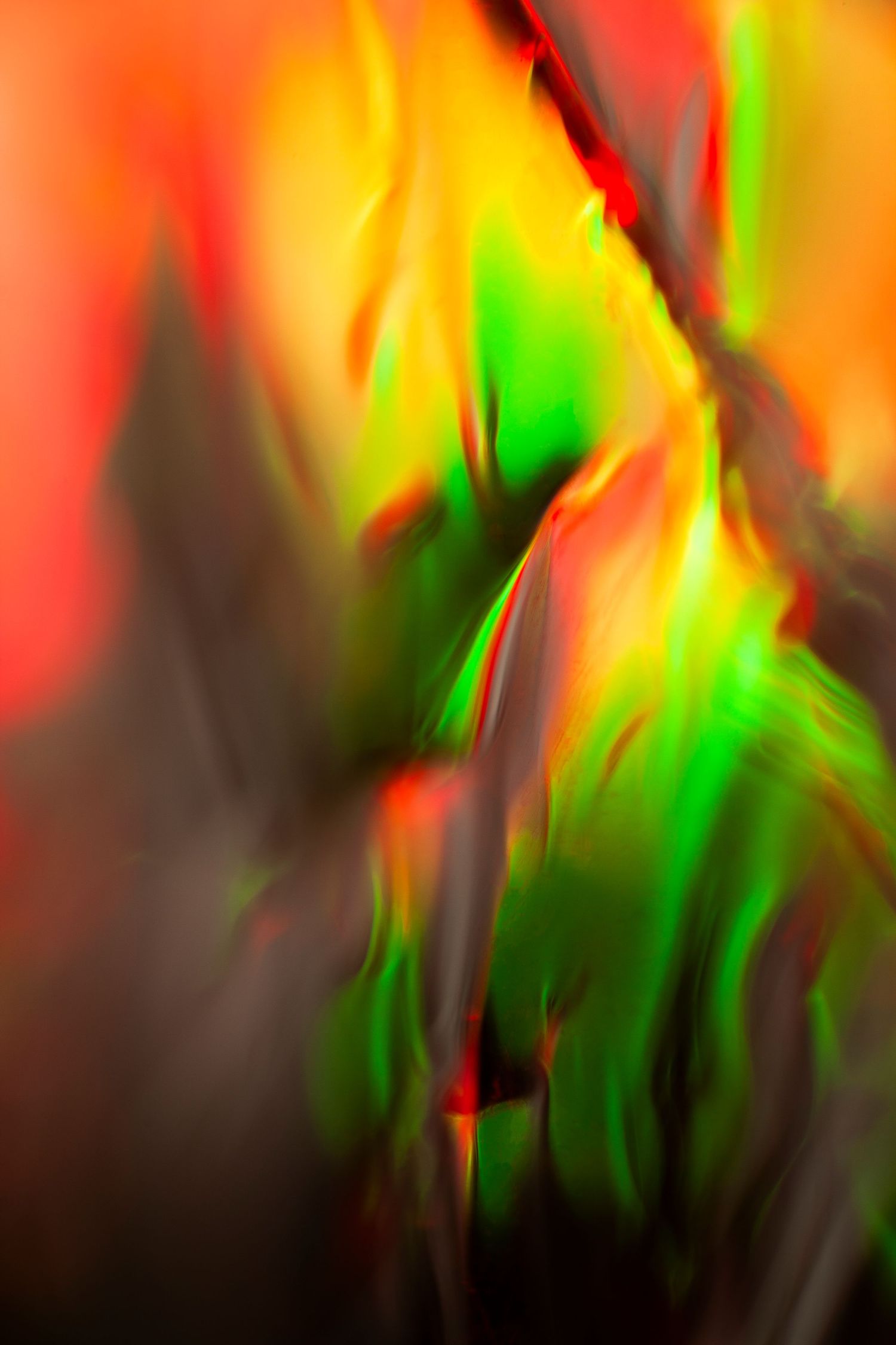 Abstract motion blur art with vibrant red, green, and yellow flame-like streaks on dark background.