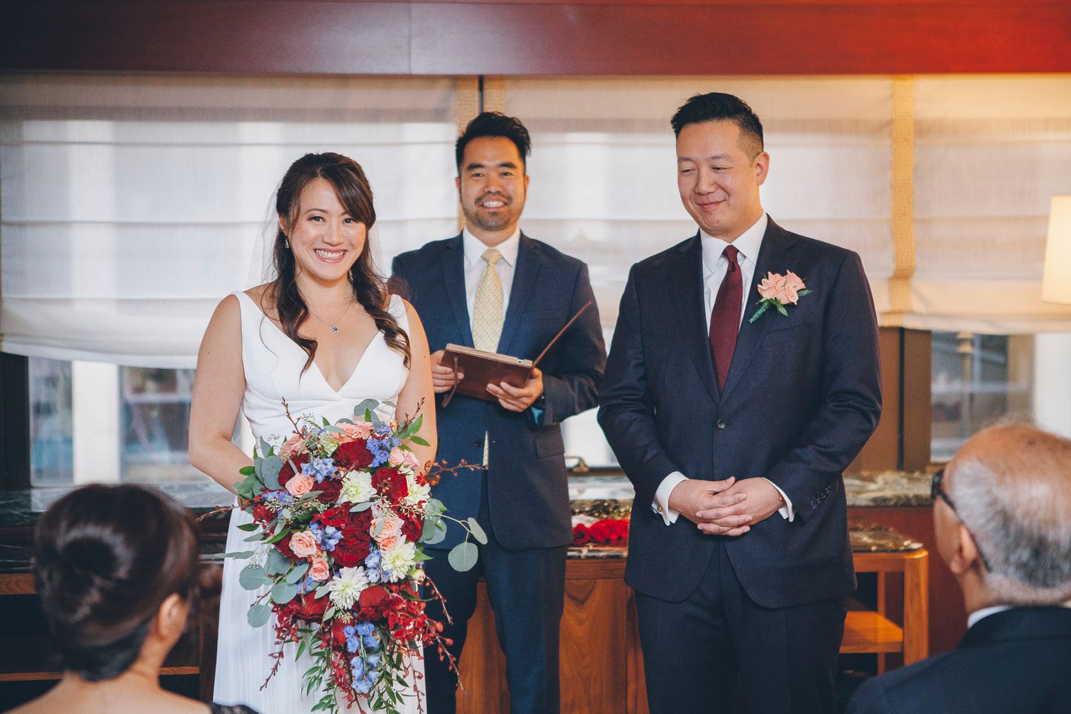 Bride and groom smiling at the altar with officiant during intimate wedding ceremony.