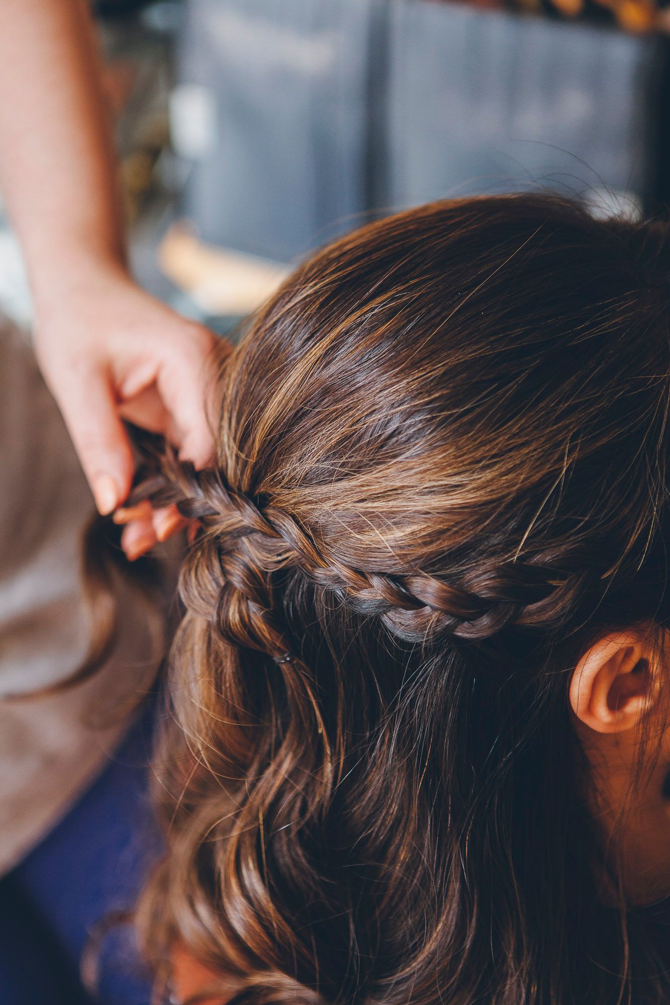 Close-up of elegant half-up braided hairstyle being styled for a wedding.