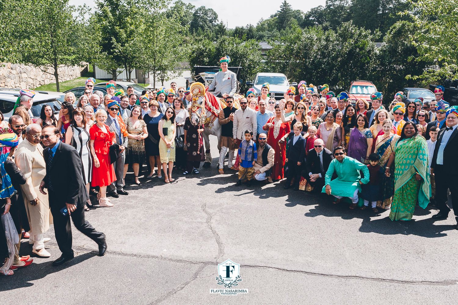 Large group of wedding guests gathered outdoors for Indian baraat wedding procession celebration.