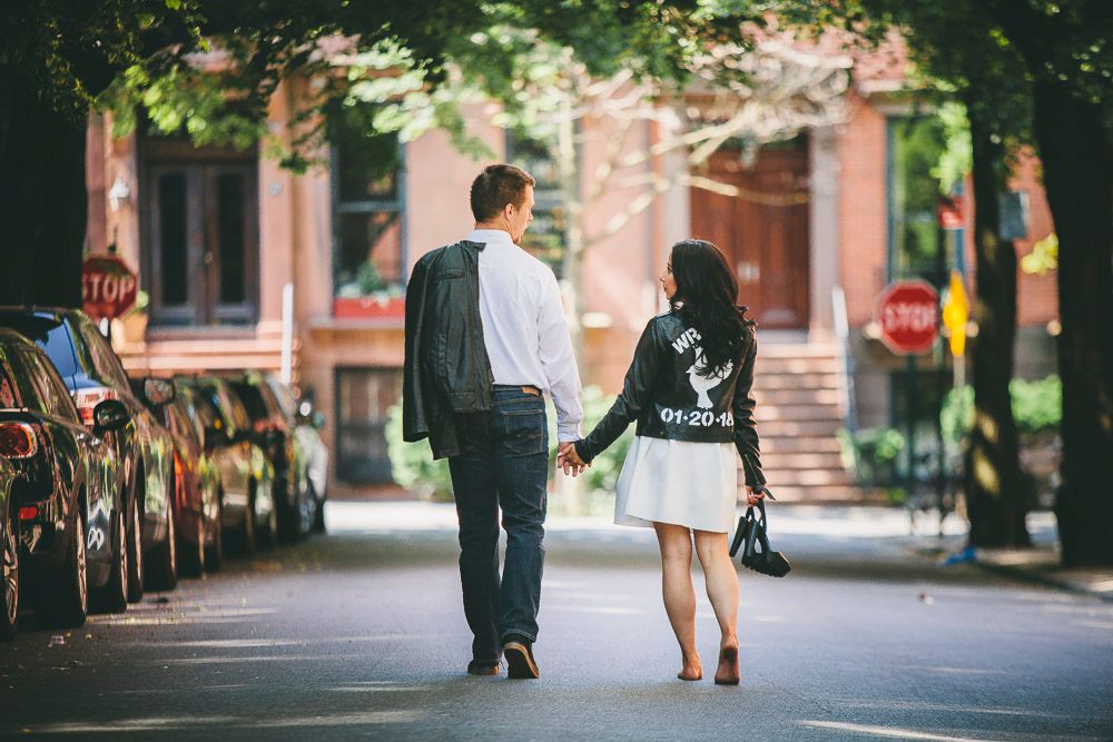 Couple walking hand in hand down a tree-lined urban street in New York City.