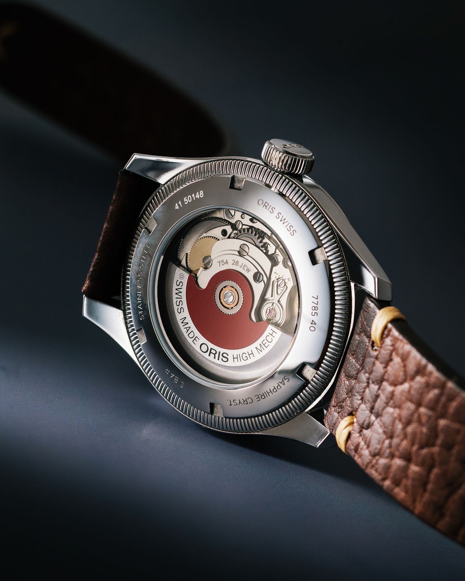 Oris High Speed watch displaying its detailed mechanical movement through a transparent caseback with brown leather strap.