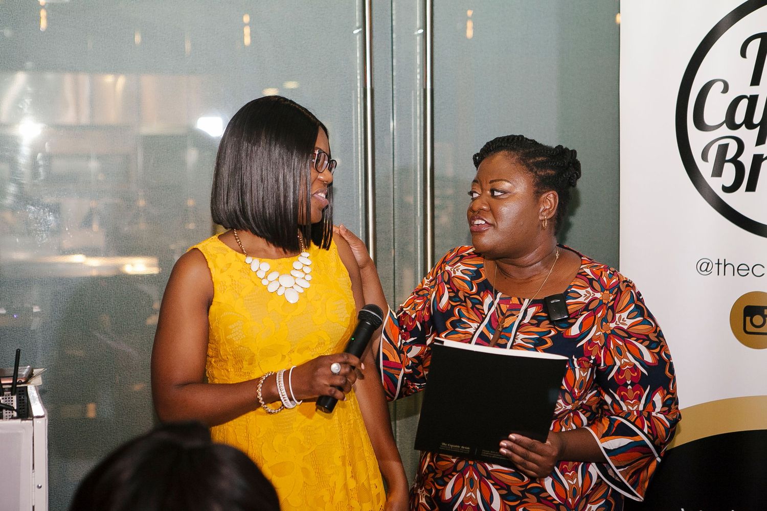 Two women conversing at The Capable Bride wedding planning event, one holding a microphone.