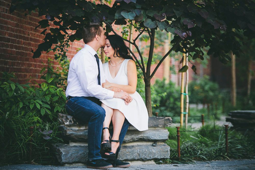 Couple sitting close together on stone steps sharing an intimate moment in a garden.