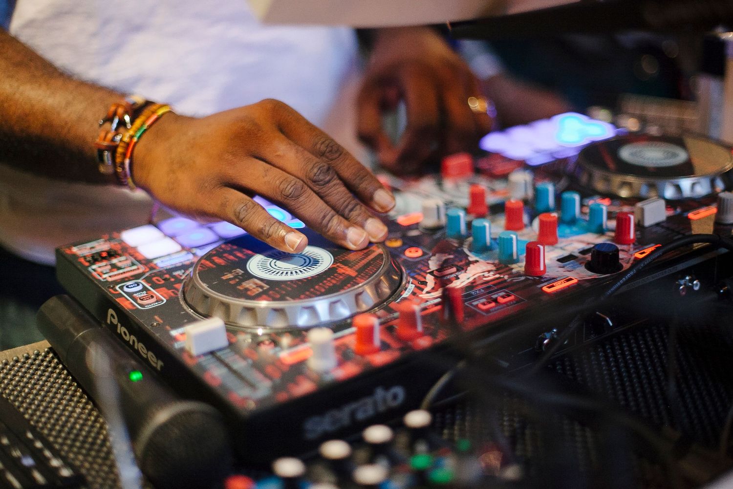 Close-up of hands operating Pioneer Serato DJ controller at live music event.
