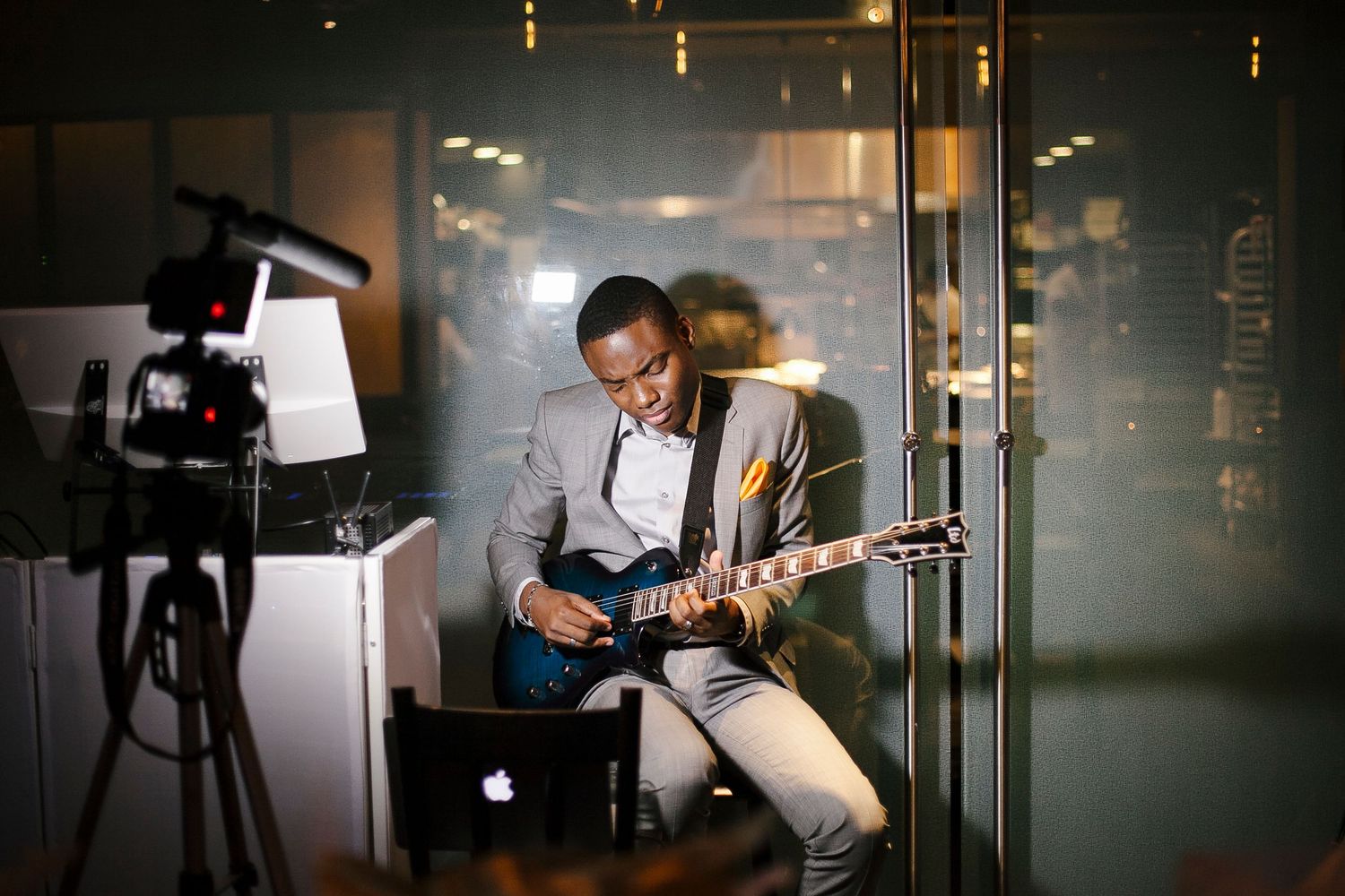 Talented guitarist in a gray suit performing energetically at The Capable Bride wedding planning event.