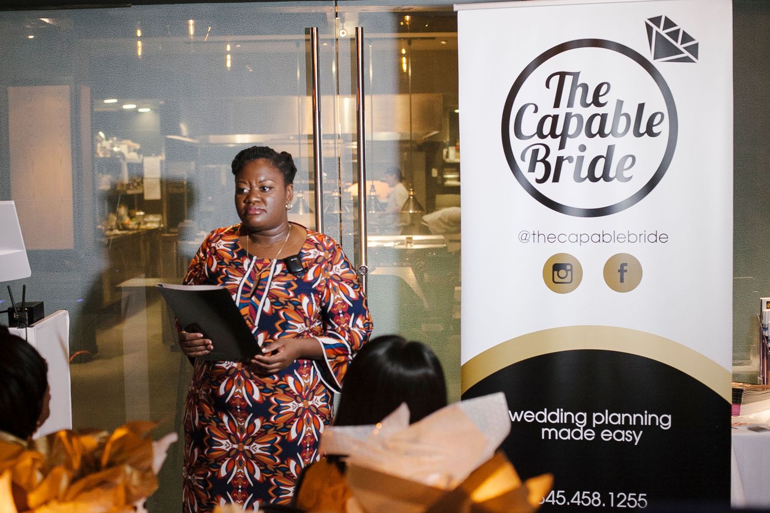 The Capable Bride founder presenting at a wedding planning event beside branded banner and signage.