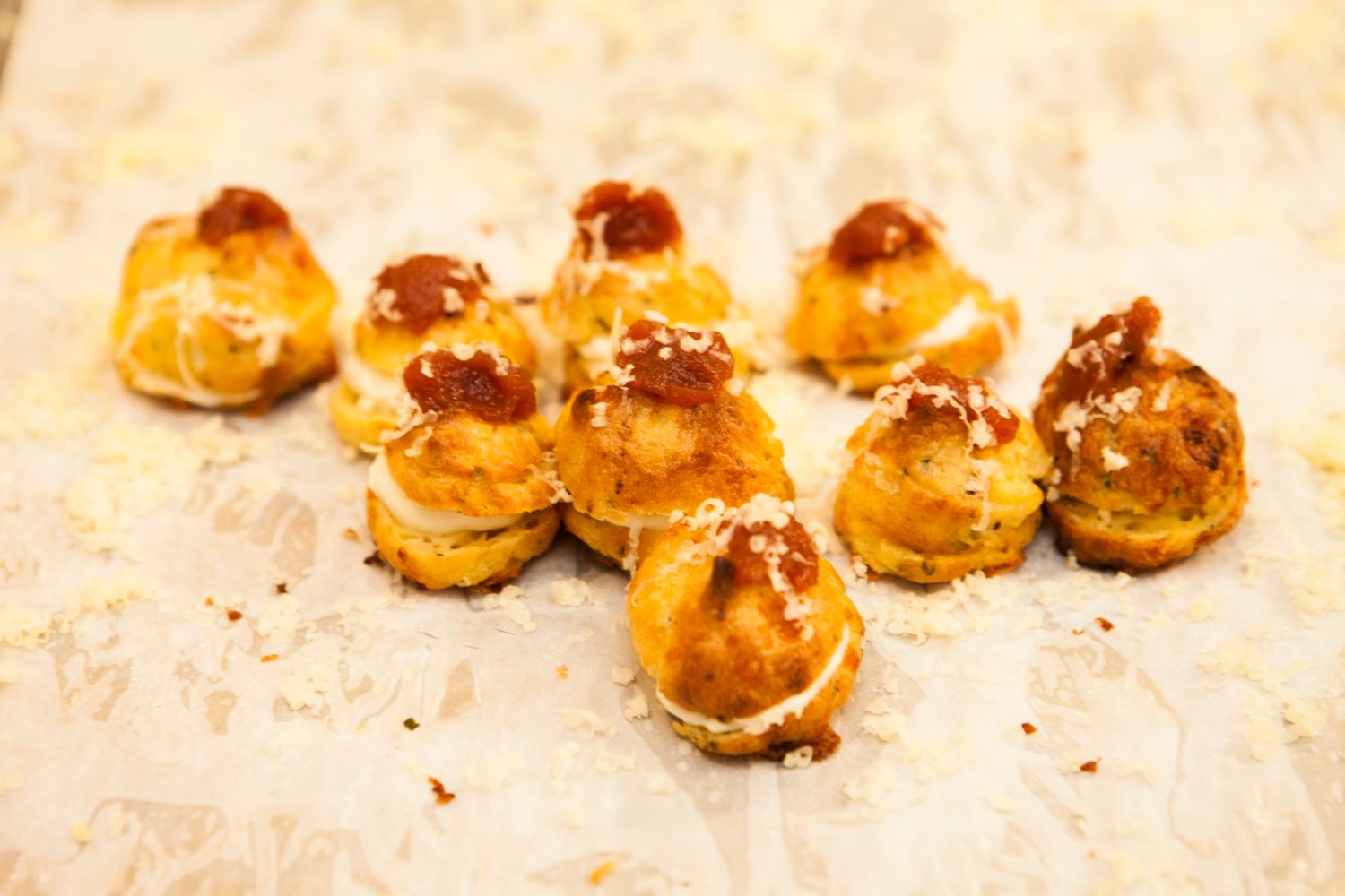 Golden baked gougeres cheese puffs with caramelized tops arranged on parchment paper ready to serve.