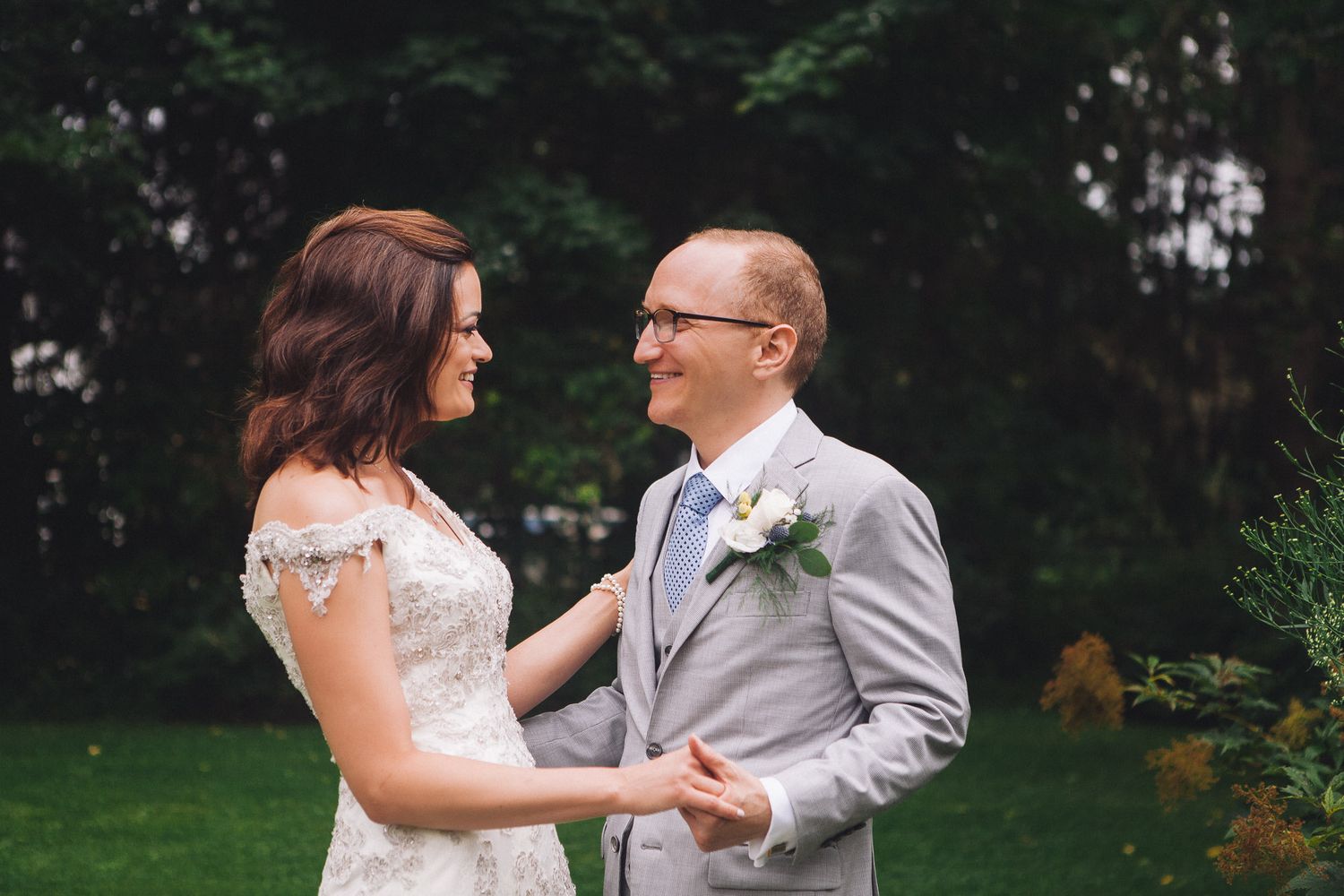 Bride and groom sharing a joyful moment together in a green garden wedding photo.