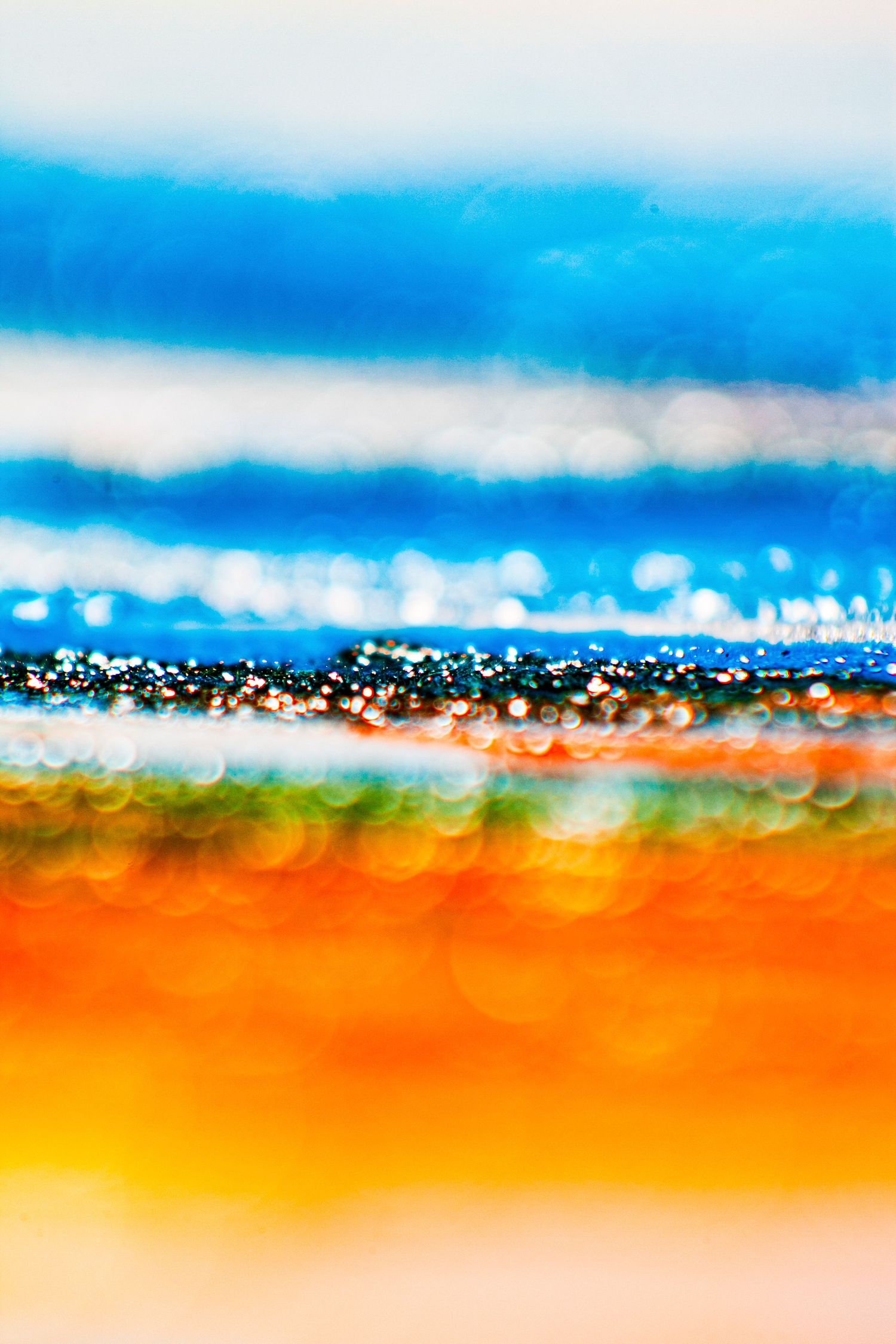 Abstract blurred bokeh background with vibrant blue, orange, and yellow horizontal bands of color.