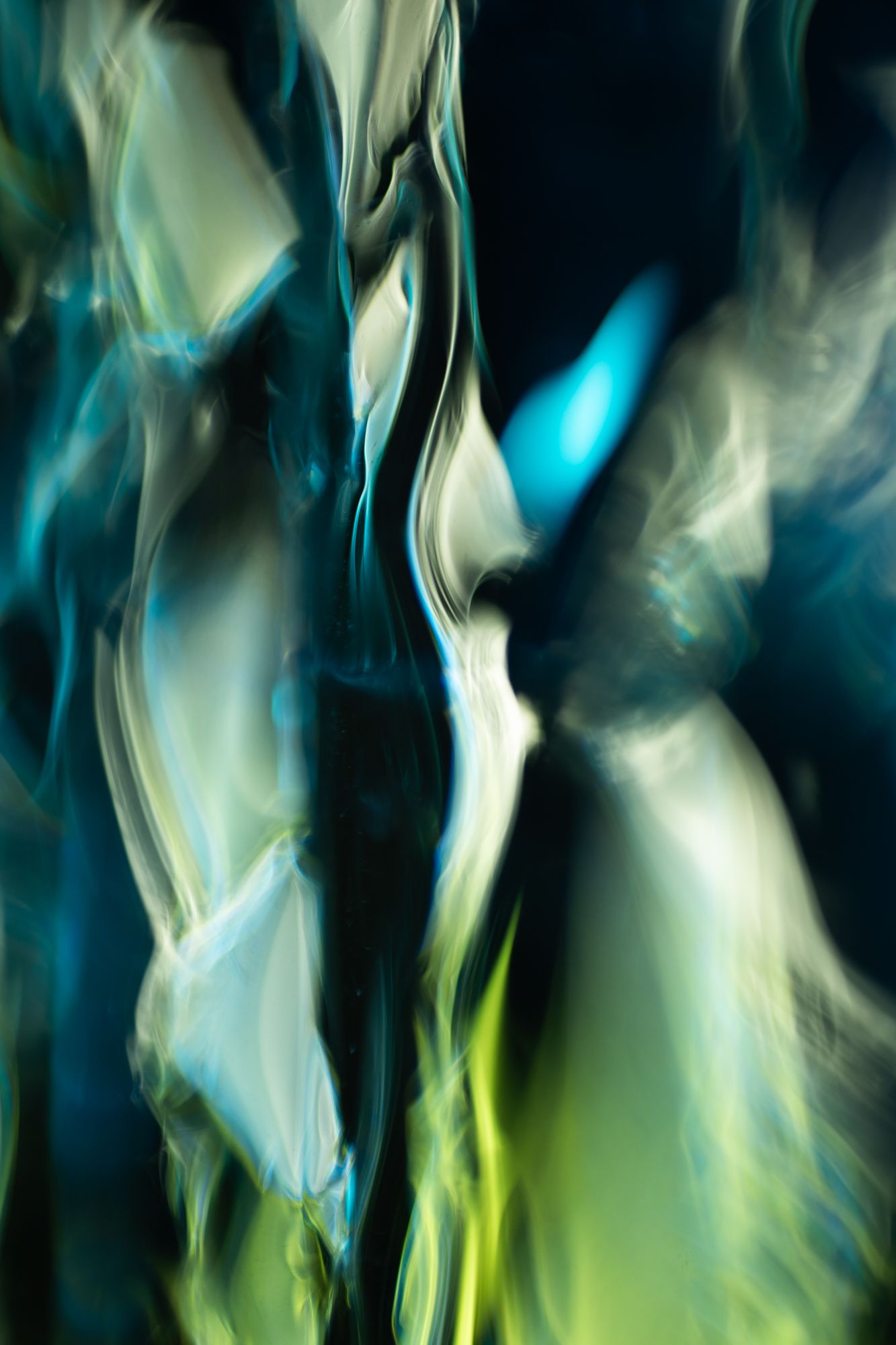 Abstract fluid art with swirling teal, blue, and lime green hues creating a dynamic, glowing motion effect on dark background.