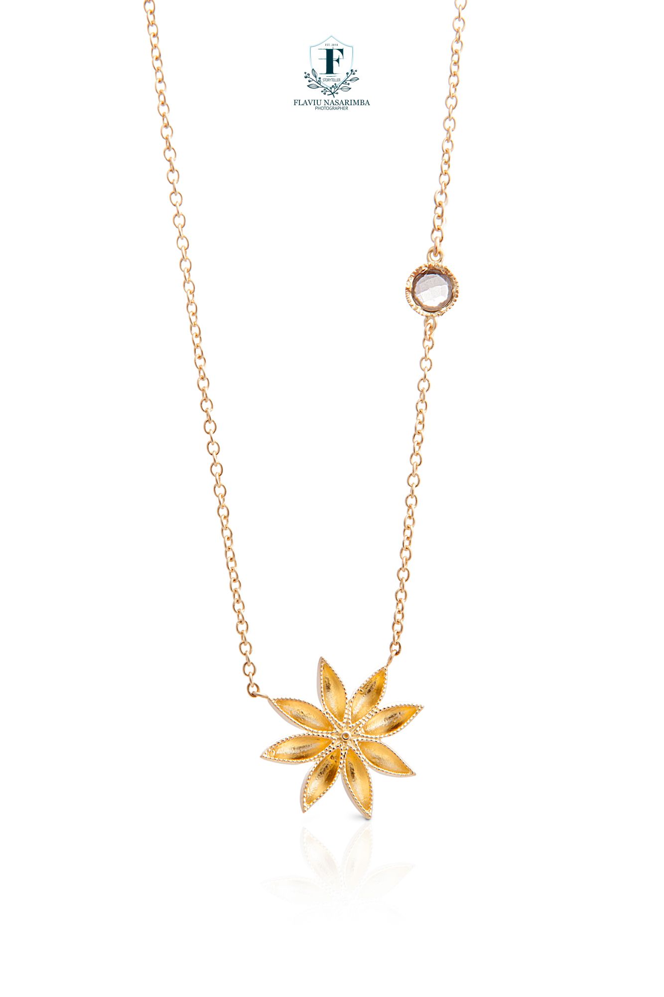 Rose gold necklace featuring a textured eight-petal flower pendant with a small moonstone accent on chain.