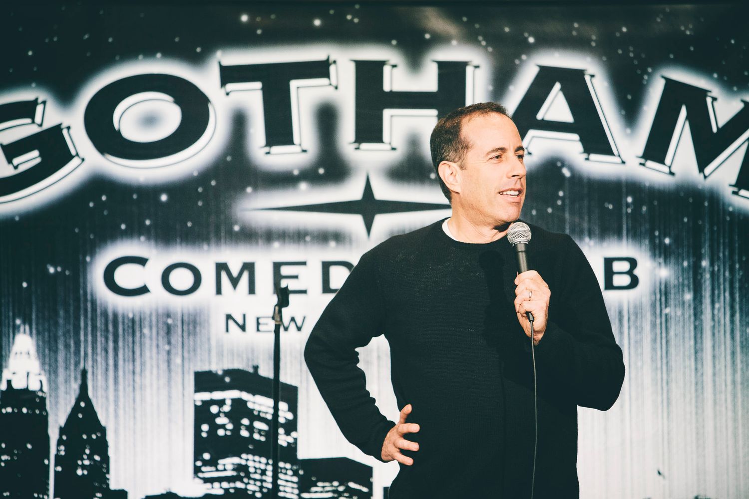 Male comedian in black shirt performing stand-up at Gotham Comedy Club NYC.