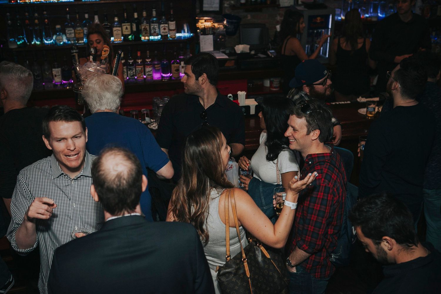 Guests mingle and socialize with drinks at a lively evening bar gathering.
